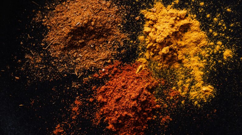 Assorted colorful dry powdered spices on black background