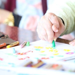 Crop elderly patient with crayons