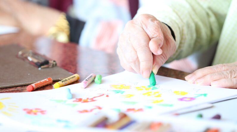 Crop elderly patient with crayons